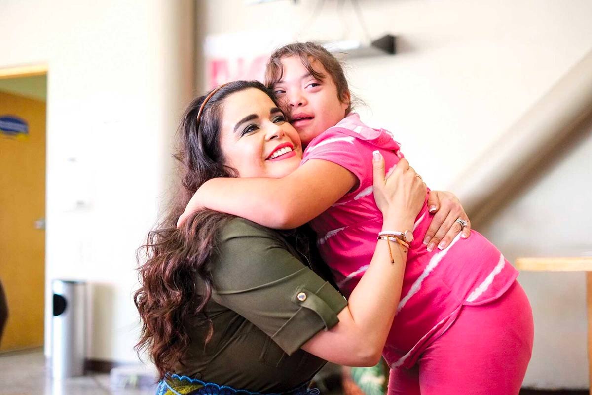 girl with disability-in pink hugging supporter